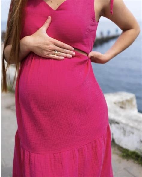 Modelka v růžovém zavinovacím těhotenském tričku Dorothy Perkins, které zdůrazňuje bříško a umožňuje snadné kojení
