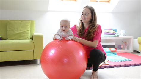 Maminka cvičí s dítětem na velkém míči (fitballu).
