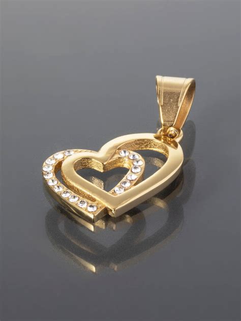 Různé typy přívěsků ze chirurgické oceli ve tvaru srdce s různými povrchovými úpravami (lesklá, zlatá).