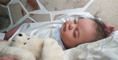 Detailní záběr na ručně vyráběnou reborn panenku s důrazem na realistické rysy a texturu pokožky.