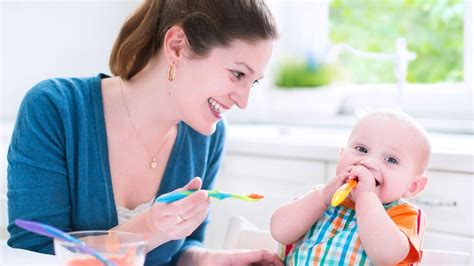 Obrázek miminka sedícího v lehátku a ochutnávajícího první příkrm